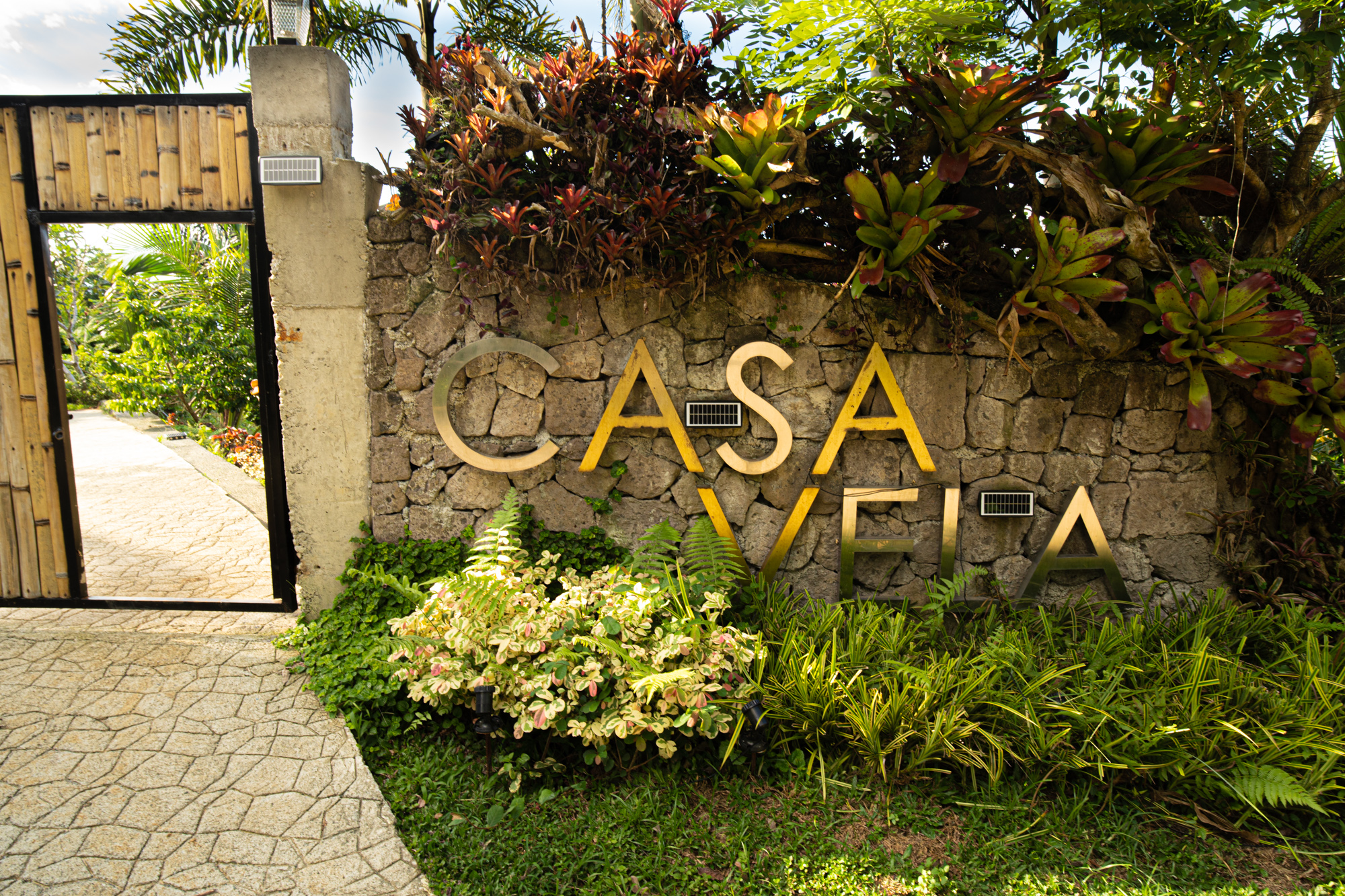 Casa Vela entrance with stone sign and tropical landscaping