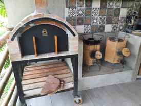 Rustic kitchen with brick wood-fired oven, traditional metal stove units, and decorative patterned tile backsplash